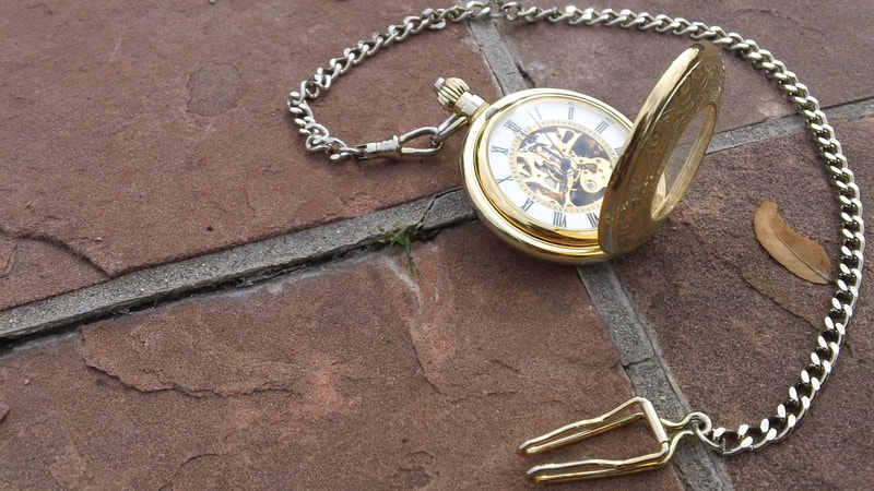 Photo of a mechanical pocket watch on the corner of some bricks.